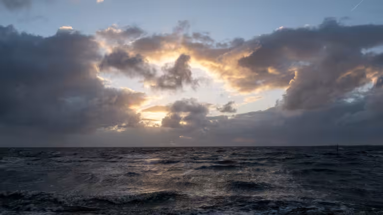 Dunkle Regenwolken über der Nordsee vor Duhnen mit aufklarendem Himmel