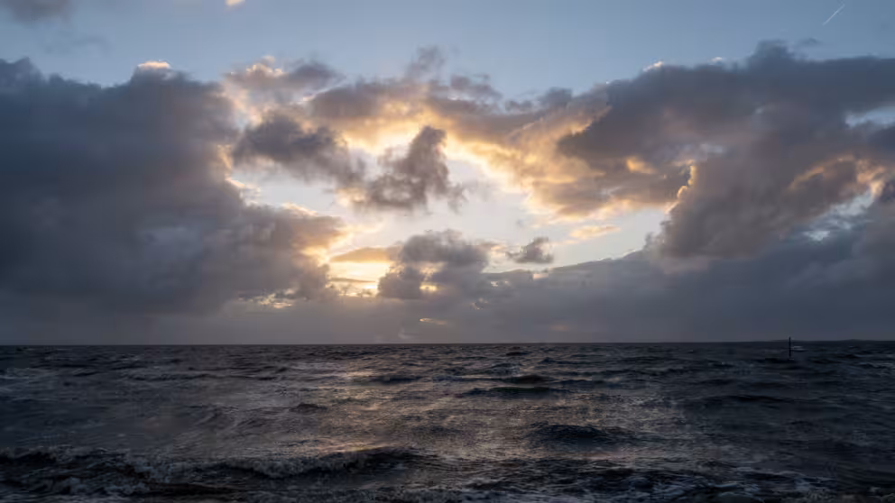Dunkle Regenwolken über der Nordsee vor Duhnen mit aufklarendem Himmel