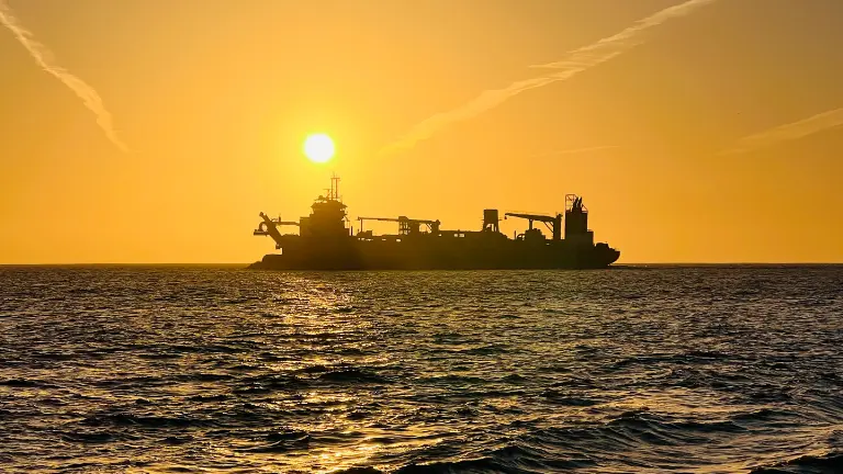 Sonnenaufgang mit goldenen Schein an der Nordsee mit vorbeifahrenden Schiff