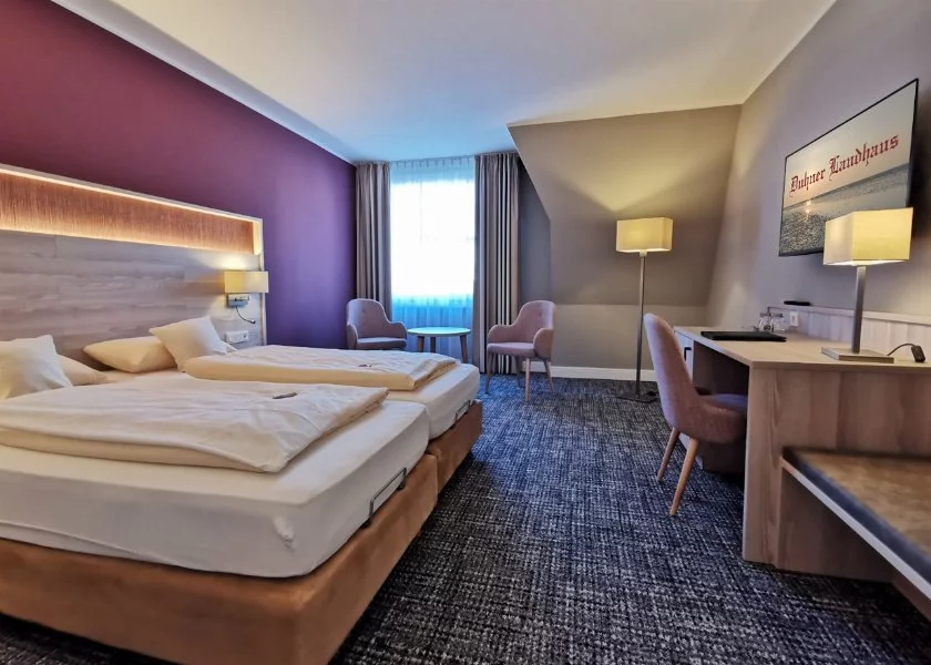 Blick in ein Doppelzimmer mit Doppelbett, Schreibtisch und Fernseher im Hotel Duhner Landhaus in Duhnen bei Cuxhaven